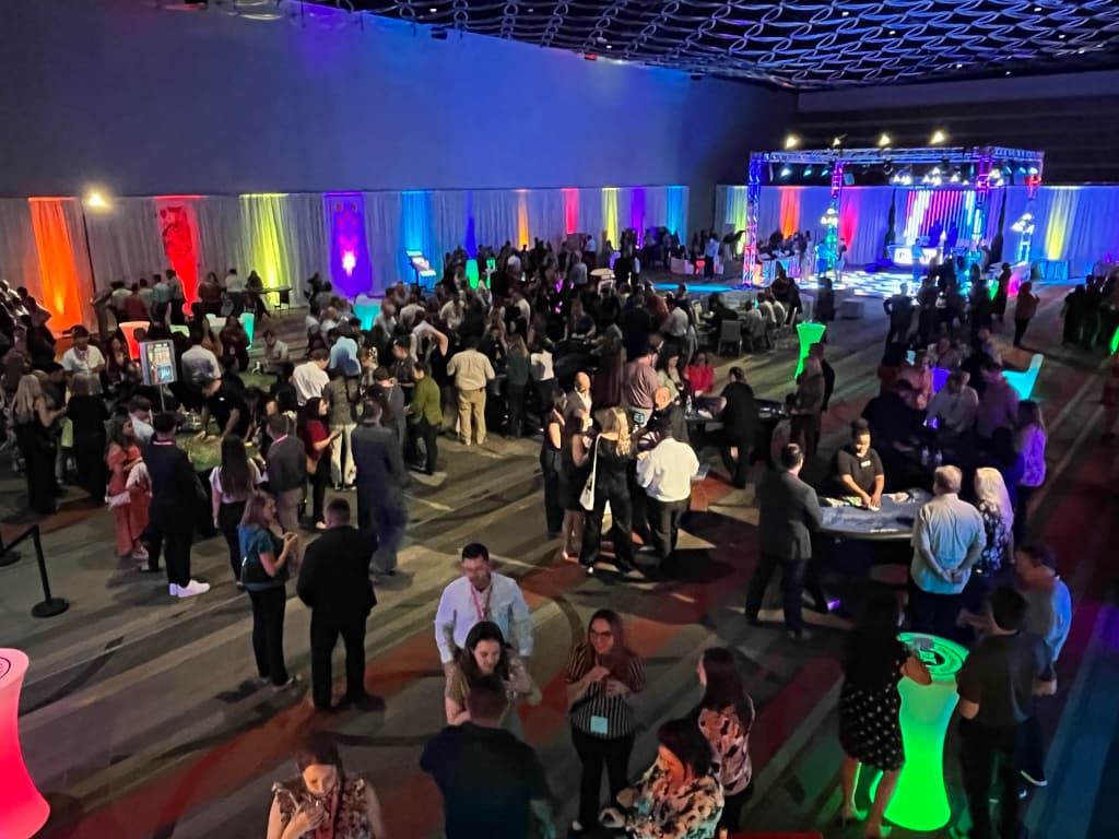 80s themed casino night with rainbow LED uplighting and guests playing at casino tables by Just Like Vegas Casino Parties